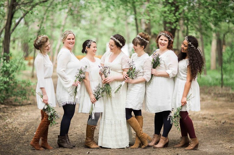 bride and bridesmaids in the woods in white dresses and colored tights and boots