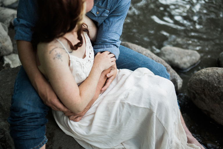 couple embracing on river rocks closeup