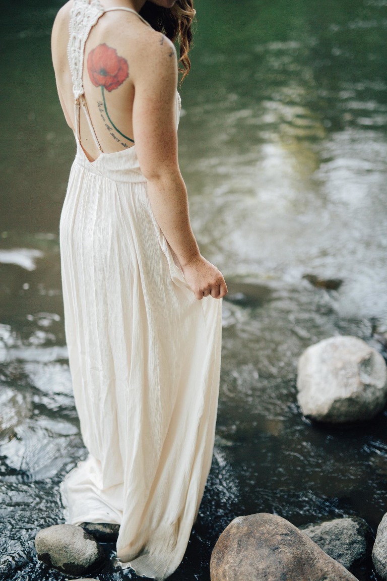 woman holding white dress standing in river
