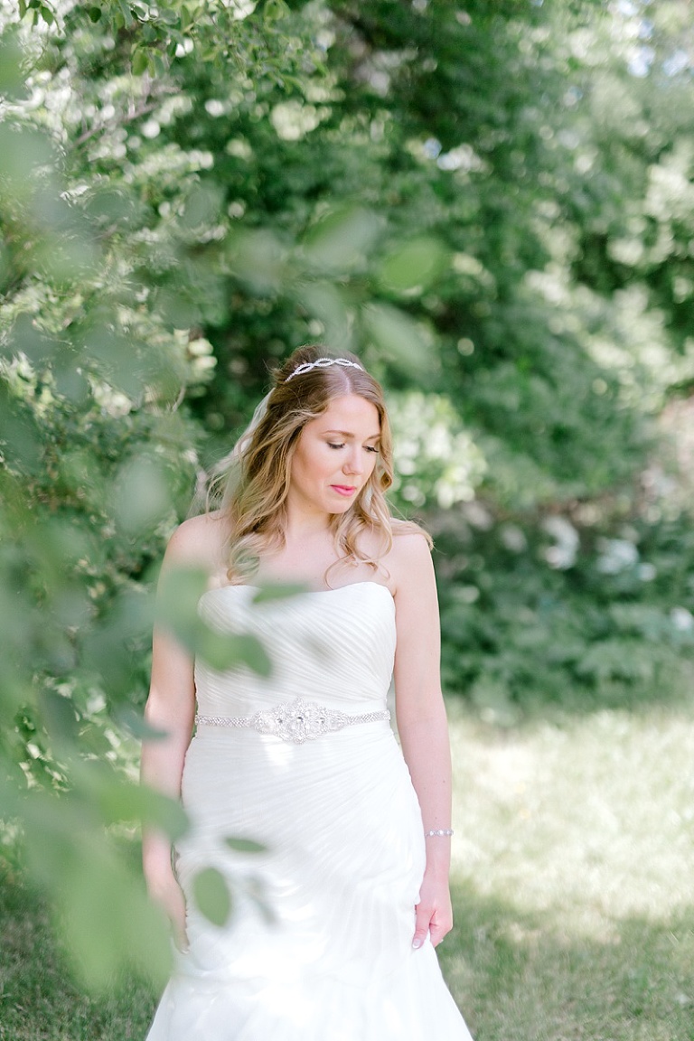 bride partially hidden in trees by fargo and fergus falls wedding photographer two birds photography brittany walsh